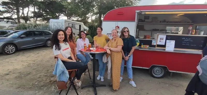 Groupe souriant réuni devant la caravane rouge en fin de journée