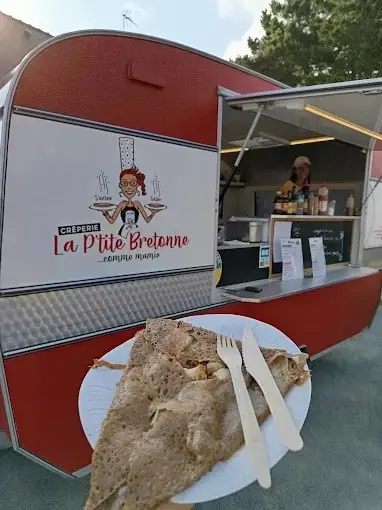 Galette complète dans une assiette, couverts en bois, devant la caravane